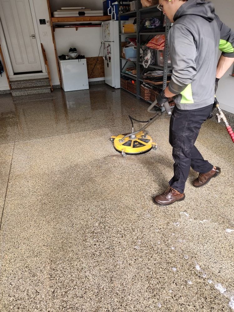 A ChicagoLand SoftWash crew member running a rotary surface cleaner across a garage floor
